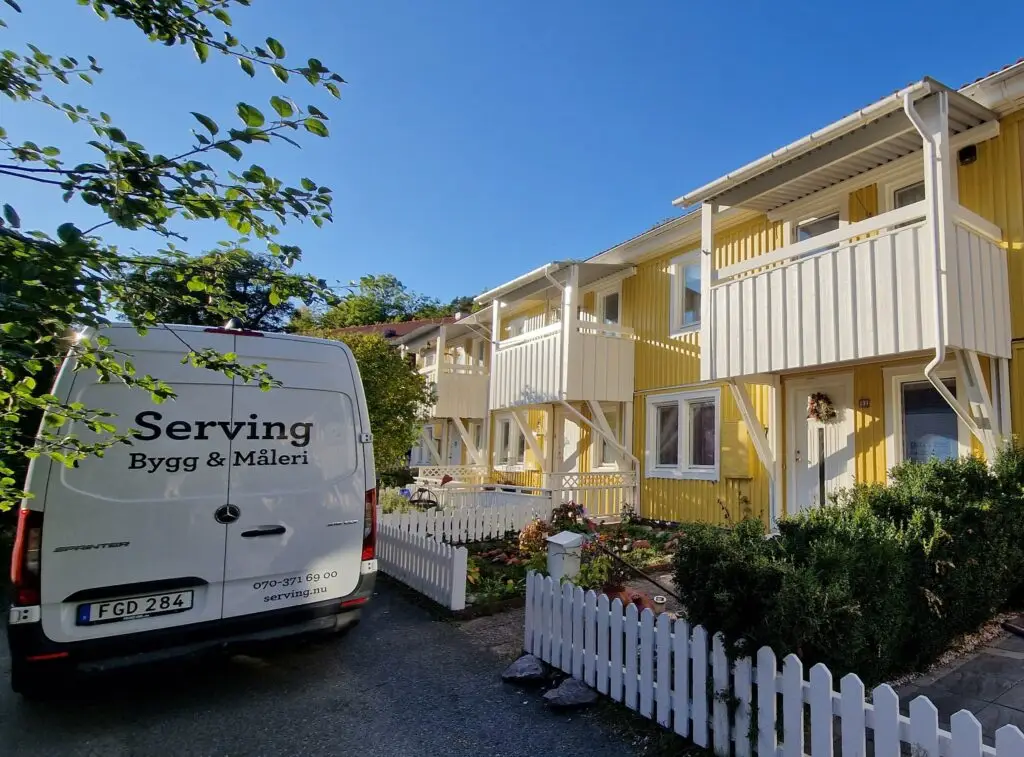 Gula radhus med nymålad fasad av Serving.nu, med firmabil i förgrunden