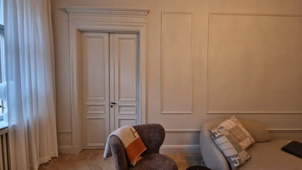 Elegant inredning med sekelskiftesdetaljer och listverk, målat av Serving.nu